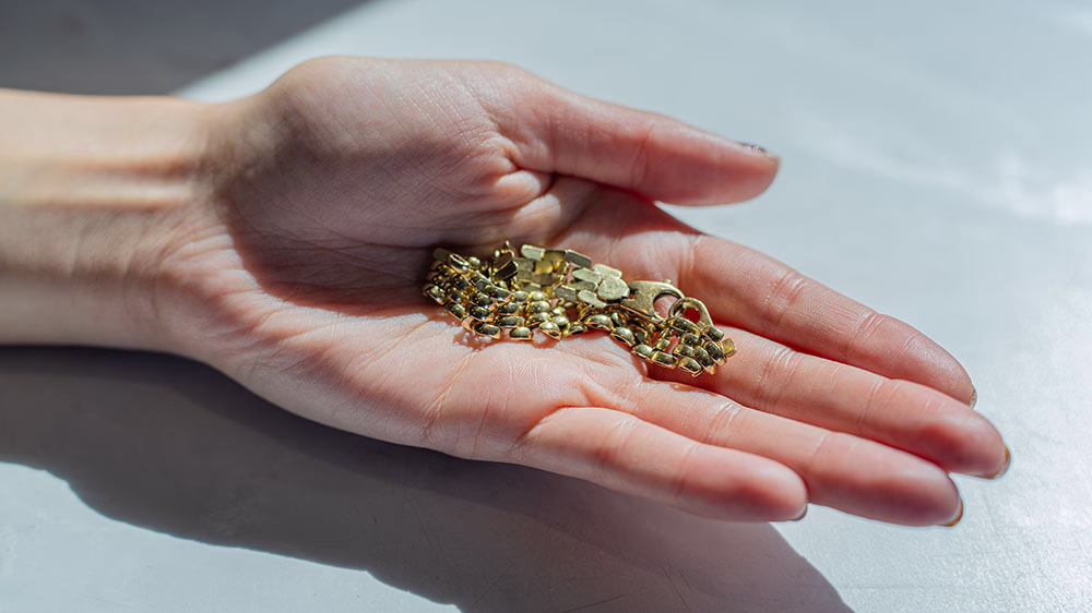 Small pieces of broken gold jewellery in an open hand